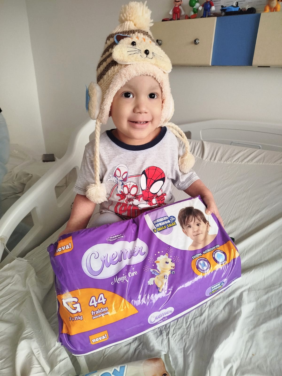 Criança em tratamento sorrindo ao receber doação na ONG Por Amor de Muitos